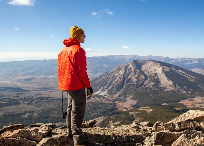 Hiker in red jacket gazing over dramatic mountain scenery