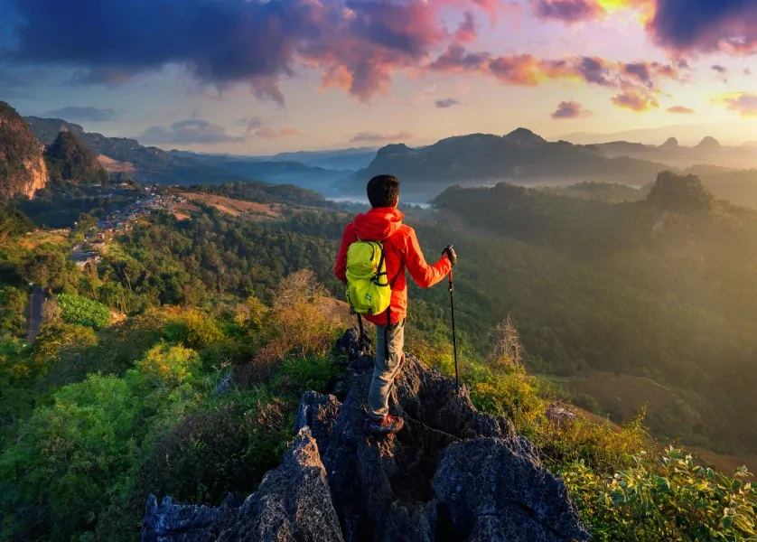 Hiker on mountain trail overlooking a misty valley